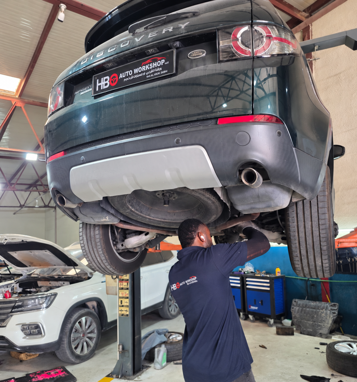 Land Rover Discovery Sport raised on a lift with a technician working underneath the rear