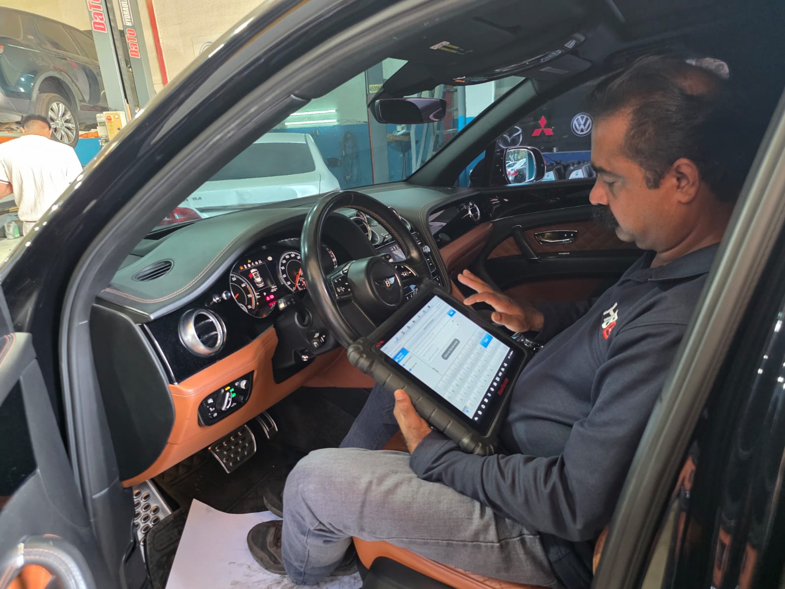Technician running a computer diagnostic check with a diagnostic tablet inside a car