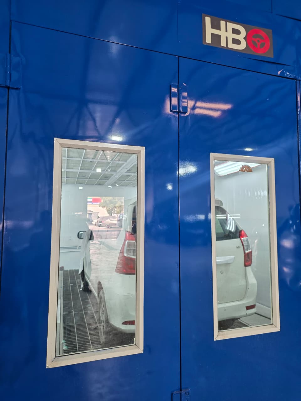 Vehicles inside the workshop's dedicated paint booth, seen through the booth doors